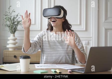 Une femme excitée et stupéfiante portant des lunettes VR et profitant d'une expérience de réalité virtuelle incroyable au travail Banque D'Images