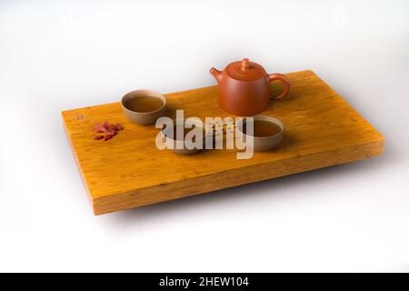 Théière en céramique et trois tasses traditionnelles pour boire du thé oriental sur une table en bois pour les cérémonies du thé sur fond blanc.Les tasses sont remplies de wi Banque D'Images