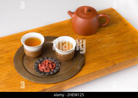 Théière en céramique et trois tasses traditionnelles pour boire du thé oriental sur une table en bois pour les cérémonies du thé sur fond blanc.Les tasses sont remplies de wi Banque D'Images