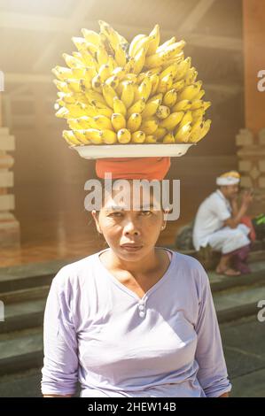 BALI, INDONÉSIE - 13.AVRIL 2018.Femme balinaise portant des bananes sur la tête à l'extérieur d'un temple.Photo éditoriale de la journée Banque D'Images