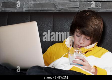 les jeunes hommes s'endorment devant son ordinateur portable tout en apprenant et en burinant un verre d'eau Banque D'Images