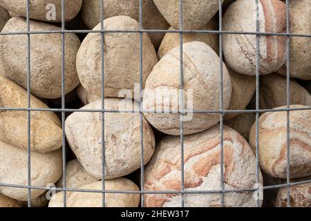 Pierres lisses rondes dans le mur de Gabion de basket, clôture en fil de fer rempli de pierres naturelles de roche Banque D'Images