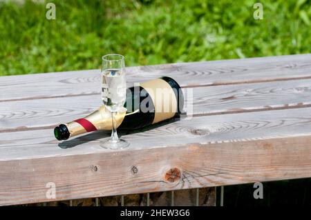 vider la bouteille de vin mousseux avec le verre posé sur un banc en bois Banque D'Images