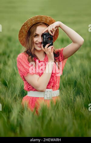 Une femme au milieu du champ prend une photo avec un appareil photo rétro. Banque D'Images