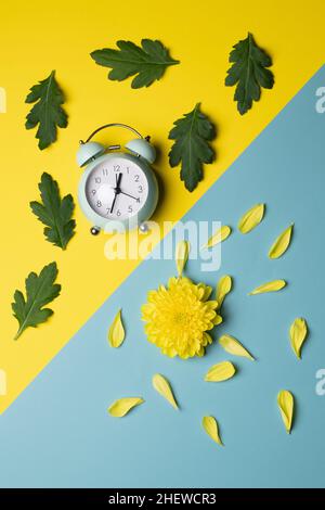 horloge et fleur décorées de feuilles et de pétales sur fond plat vertical, en diagonale Banque D'Images