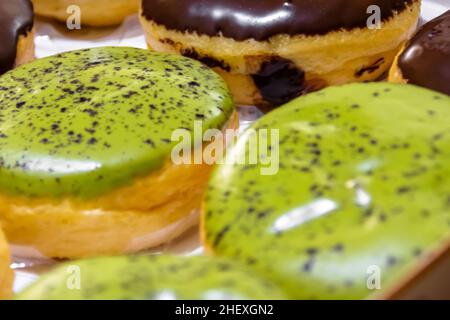 Gros plan de délicieux et savoureux beignets au thé vert avec beignets au chocolat glacis à côté Banque D'Images