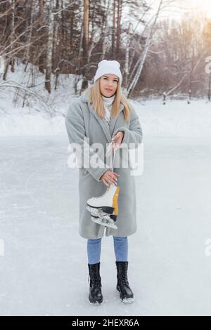 Jolie jeune femme avec patins à glace sur la patinoire.Une fille va patiner sur la glace en hiver Banque D'Images
