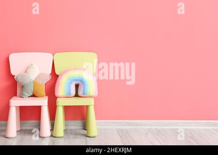 Chaises d'enfant avec de jolis jouets près du mur de couleur Banque D'Images