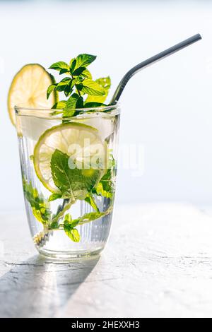 Mojito cocktail en verre avec citron vert, glace et menthe servi sur un fond lumineux Banque D'Images