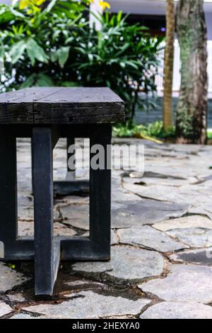 banc public en bois dur brun rugueux avec stands en métal noir sur le parc de la ville Banque D'Images