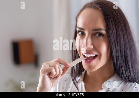 Une bonne brunette met une gomme à mâcher dans sa bouche en regardant dans l'appareil photo. Banque D'Images