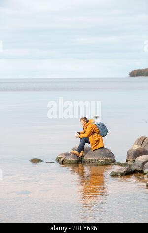 Homme caucasien assis sur le rocher en face du lac et appréciant la vue.Homme se reposant après une longue marche Banque D'Images