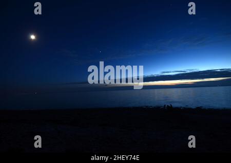 Vue sur la mer au crépuscule avec la Lune, Jupiter, Saturne et Vénus juste au-dessus des nuages.Les planètes semblent se tenir dans une ligne, c'est ce que l'on appelle l'ecli Banque D'Images