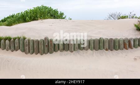 Dunes de sable de plage avec des poteaux en bois insérés pour agir comme une barrière aux vents changeant le paysage. Banque D'Images