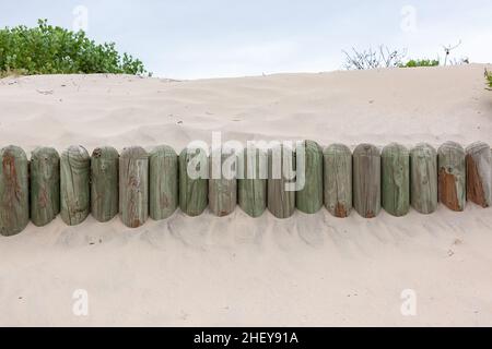 Dunes de sable de plage avec des poteaux en bois insérés pour agir comme une barrière aux vents changeant le paysage. Banque D'Images