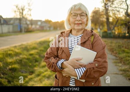 50s femme tenant main tablette PC numérique en automne domaine de la nature au coucher du soleil, en ligne, personnes âgées et utilisation de la technologie moderne Banque D'Images