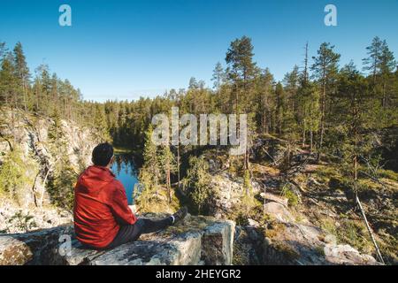 Le voyageur se trouve sur un rocher élevé et observe un beau lac naturel dans le parc national de hiidenportti, Sotkamo, dans la région de kainuu, en Finlande.Randonnée dans le Finni Banque D'Images