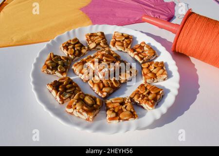 Barres chikki de cacahuète ou chikky de Moongfalli avec Kite et fil de bobine avec fond blanc.Makar sankranti, uttarayan, pongal, Lohri affiches du festival f Banque D'Images