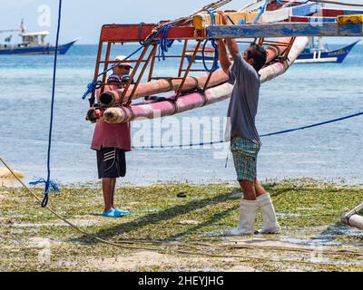 Travaux d'entretien sur le déclencheur d'un bateau de pêche traditionnel philippin, un basigan, à marée basse dans le village de Tinoto, Maasim dans la Sarang Banque D'Images