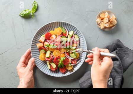 Femme prête à manger Panzanella salade italienne avec tomates, fromage et croûtons croustillants.Vue de dessus.Cuisine italienne traditionnelle.Panzanella végétarien il Banque D'Images