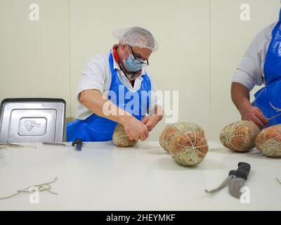 Travailleur spécialisé couture et finition des coupes à froid de culatello, de coppa et de prosciutto dans l'usine de fabrication de produits délicats de Parme en Italie Banque D'Images