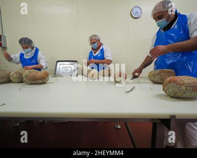 Travailleur spécialisé couture et finition des coupes à froid de culatello, de coppa et de prosciutto dans l'usine de fabrication de produits délicats de Parme en Italie Banque D'Images