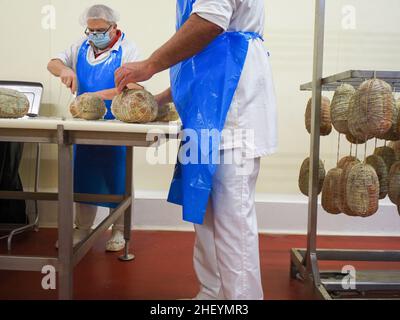 Travailleur spécialisé couture et finition des coupes à froid de culatello, de coppa et de prosciutto dans l'usine de fabrication de produits délicats de Parme en Italie Banque D'Images