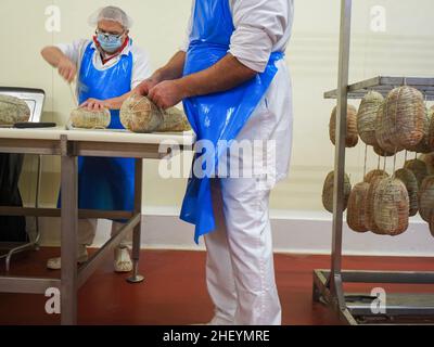 Travailleur spécialisé couture et finition des coupes à froid de culatello, de coppa et de prosciutto dans l'usine de fabrication de produits délicats de Parme en Italie Banque D'Images