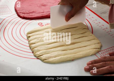 Chef à la main diviser la pâte avec un couteau en plastique en portions pour faire du petit pain ou de la pizza Banque D'Images