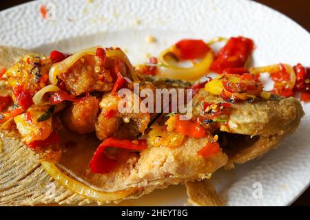 Carpe aigre-douce épicée sur une assiette blanche qui est l'un des plats proposés par un restaurant de fruits de mer. Banque D'Images