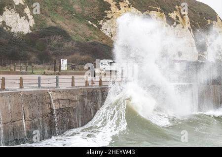 Une femme regarde les vagues claquer contre le mur du port de Newhaven comme une forte pluie et des vents de 40 mille par heure battent la côte sud de la Grande-Bretagne. Newwave Banque D'Images