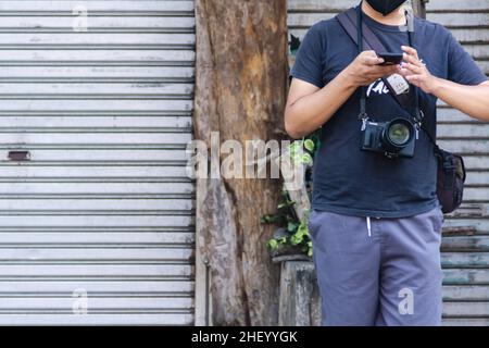 Homme photographe de rue debout sur le trottoir de la façade de la porte de garage fermée Banque D'Images