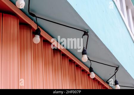 devant fermé avec porte à roulettes en boîte de couleur rose et guirlande lumineuse accrochée aux murs vert pastel Banque D'Images