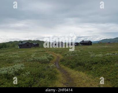 Vue sur le chalet en bois de la cabane touristique d'Arasluokta au village sami sur les rives du lac Arasluokta.Plaine de paysage de Laponie avec arbustes et montagne cachée Banque D'Images