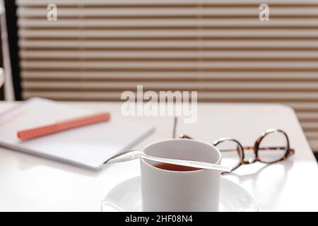 Une tasse de thé sur une table blanche avec articles de papeterie Banque D'Images