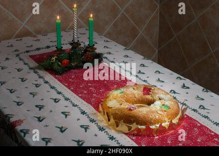 Un gâteau de beignet géant rempli de crème fouettée douce et de truffe au chocolat avec des fruits confits, des amandes et du sucre glace sur une nappe de Noël avec l Banque D'Images