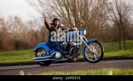 Homme sur une grosse moto bleue agitant à la caméra Banque D'Images