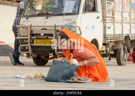 Une femme indienne âgée portant une orange sari vend des collations alimentaires aux touristes à Udaipur, Rajasthan, Inde, Asie du Sud Banque D'Images