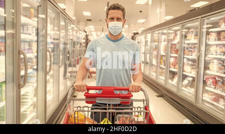 shopper dans le masque de protection avec panier d'achat de nourriture à l'épicerie, supermarché Banque D'Images