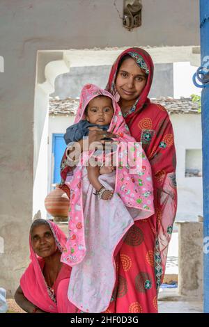 Une jeune mère indienne locale portant un sari rose berce son bébé dans sa maison dans le village de Nagda, près d'Udaipur, Rajasthan, Inde, Asie du Sud Banque D'Images