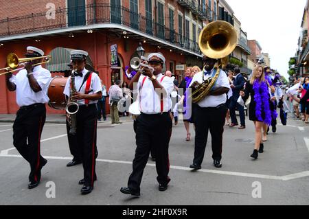 Un groupe de jazz en laiton de deuxième ligne s'amande sur Bourbon Street dans le quartier français de la Nouvelle-Orléans, tandis que les amateurs de fête défilent et dansent derrière eux Banque D'Images