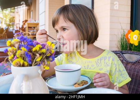 La petite fille a le petit déjeuner dans le café Banque D'Images