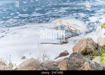 Rivière polluée, mousse dans une eau près de la rive. Banque D'Images