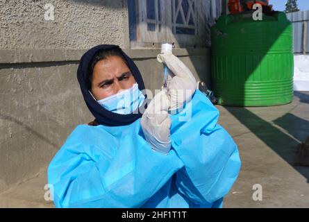 Naznena Akhtar, une travailleuse de santé, se prépare à administrer une dose de vaccin Covishield à GH Rasool à l'extérieur d'une maison pendant une campagne de vaccination porte à porte COVID-19 sur le village de Malvaa à Snowbound, dans le district de Baramulla au Cachemire du Nord, à environ 56 kilomètres de Srinagar, la capitale estivale du Cachemire indien.Malgré le froid et les routes complètement enneigées, ces agents de santé de la vallée du Cachemire braisent les conditions météorologiques difficiles et vont de porte à porte pour vacciner les gens.dans une zone lointaine de la vallée du Cachemire, une équipe de travailleurs médicaux transportant des boîtes de vaccination et d'autres coéquipiers Banque D'Images