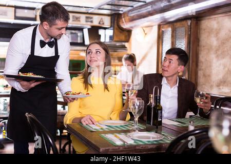 Homme serveur est apporte ordre à couple qui ont le dîner et boire du vin Banque D'Images