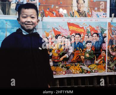 Garçon à Beijing, 1957, avec des affiches montrant des travailleurs prospères et heureux Banque D'Images