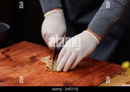 L'homme coupe du poisson frit, le processus de cuisson de la soupe Suquet de Peix avec des pommes de terre Banque D'Images