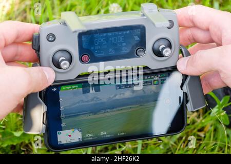 Gros plan sur le contrôleur de console de drone avec le téléphone portable dans les mains de man avec l'herbe sur l'arrière-plan.Photographie aérienne de la nature.Janvier 2022, Poprad, Slovaquie. Banque D'Images