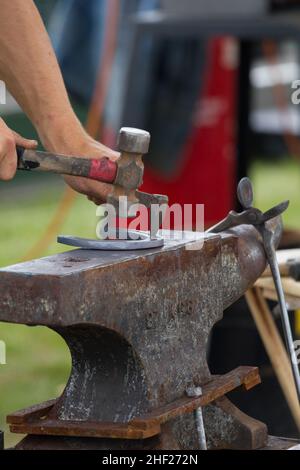 Farrier faisant des trous de clou sur une chaussure de cheval, sur une enclume. Banque D'Images