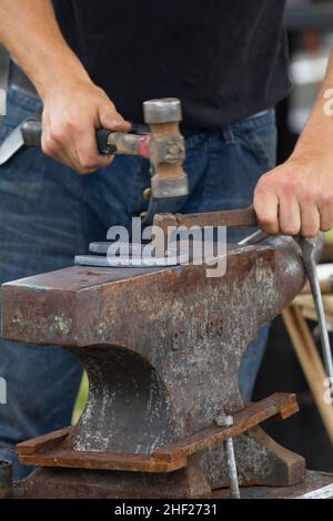 Farrier faisant des trous de clou sur une chaussure de cheval, sur une enclume. Banque D'Images